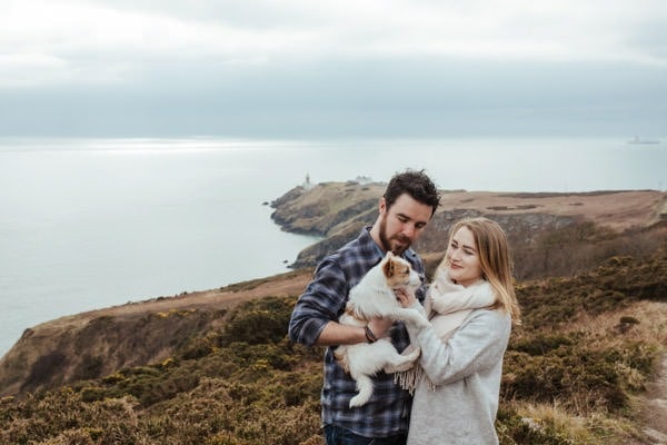 engaged couple on howth cliffs holding their dog