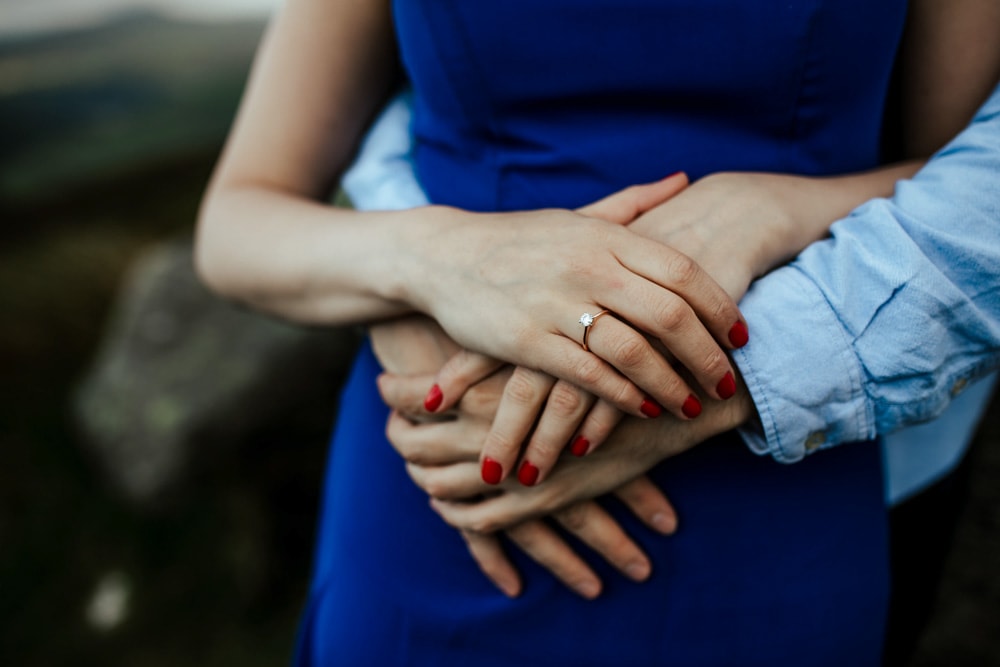 couple holding hands showing engagement ring