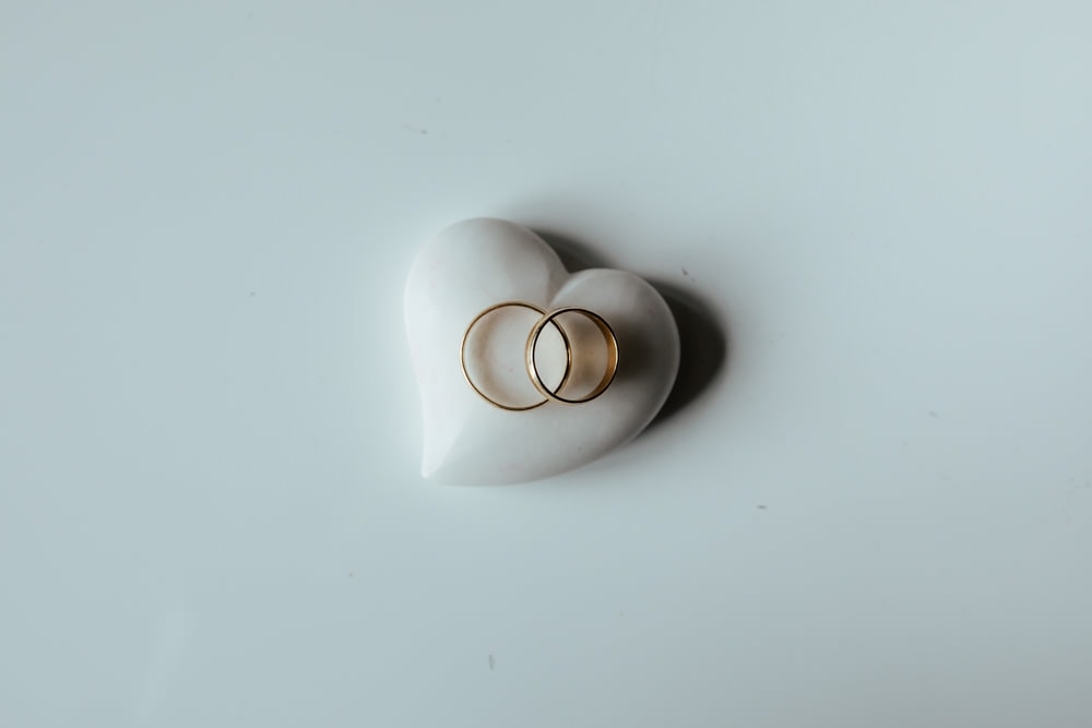 gold wedding bands on a white heart shaped stone