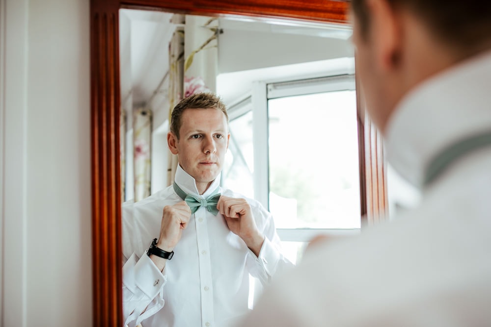 groom putting on his bow tie