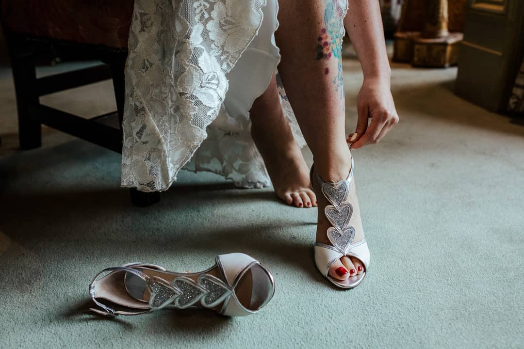 bride putting on her white betsy johnson bridal shoes with hearts vintage wedding shoes