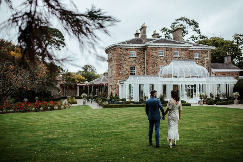 bride and groom walking to marlfield house view of the conservatory