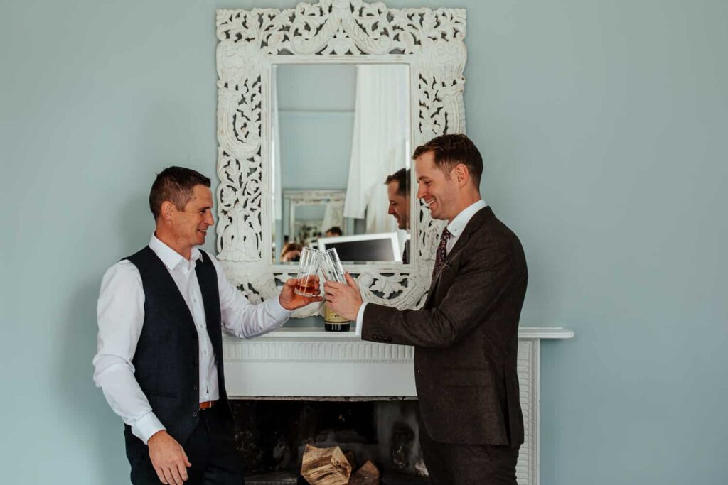 groom and best man having a whiskey on wedding morning